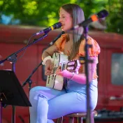 Jasmin Nell singt mit Gitarre auf der Bühne